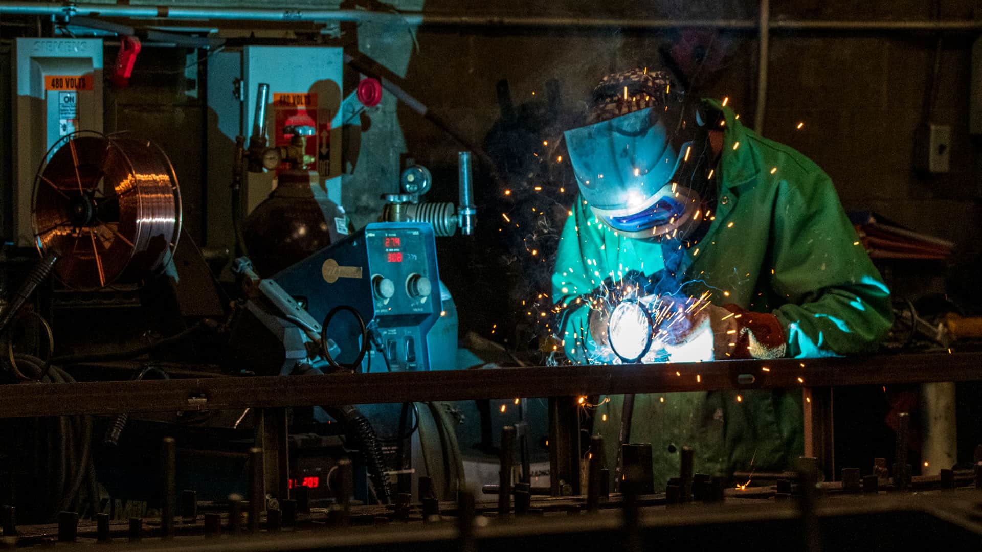 Frontal shot of a man welding in a blue glow